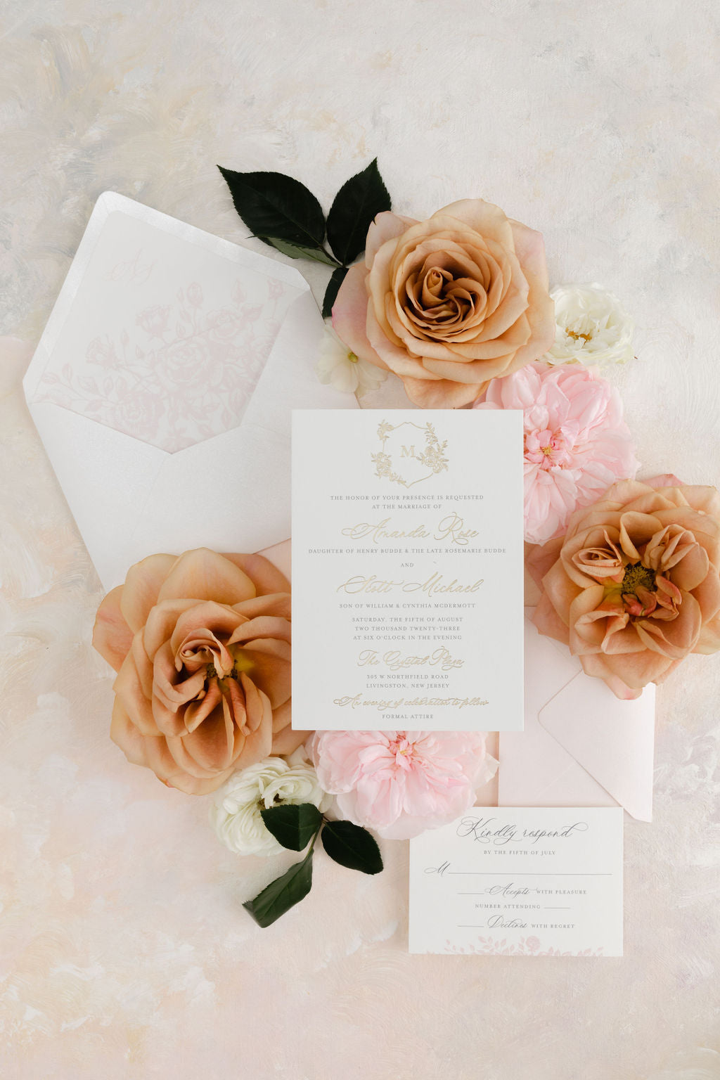 An elegant wedding invitation displayed with floral monogram and gold foil details, accompanied by etched roses envelope of the Amanda Rose Suite.